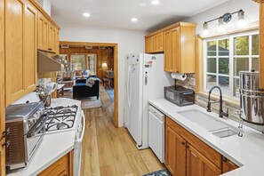 A kitchen with wooden cabinets, a stove, a refrigerator, and a microwave. - HOT TUB! PET FRIENDLY! Basketball! Fire Pit! EV Charger! A/C! (Big Bear City)