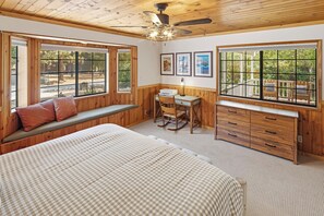 A bedroom with a bed, a desk, a rocking chair, and large windows. - HOT TUB! PET FRIENDLY! Basketball! Fire Pit! EV Charger! A/C! (Big Bear City)