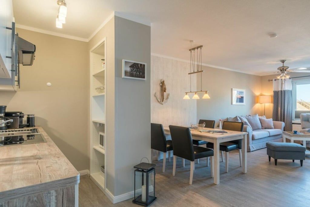 Un salon moderne comprenant un coin repas, une cuisine et un escalier.