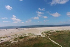 Een kustlandschap met een zandstrand, een onverharde pad en een heldere lucht.