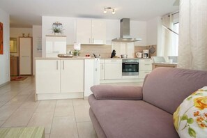 Une cuisine moderne avec des meubles blancs, un îlot central et un coin repas comprenant une table et des chaises.