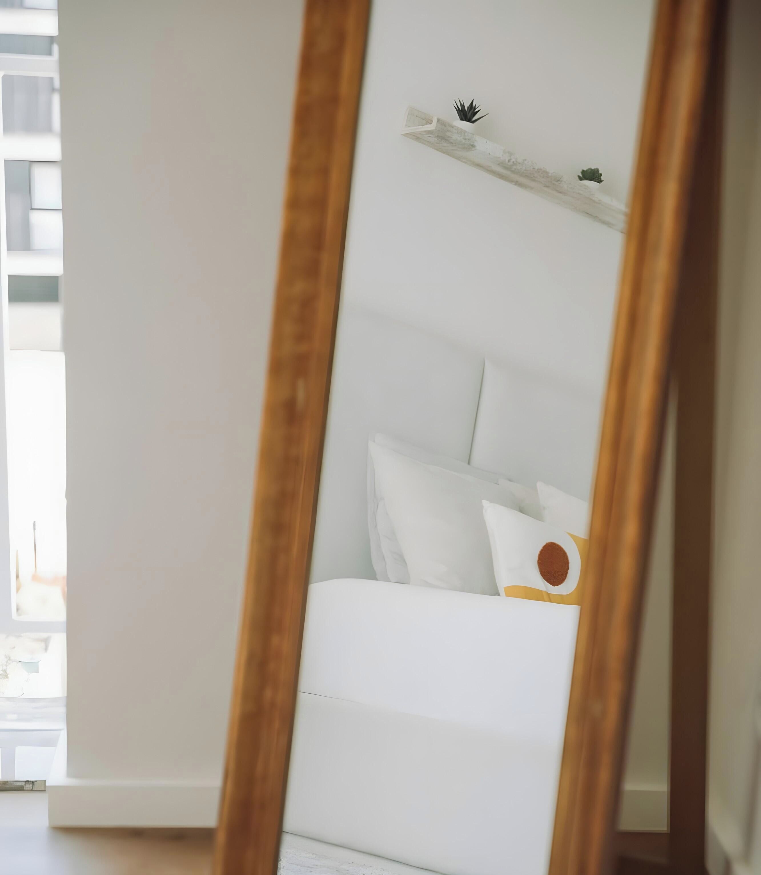 Une chambre avec un lit blanc, un plancher en bois et un mur blanc.