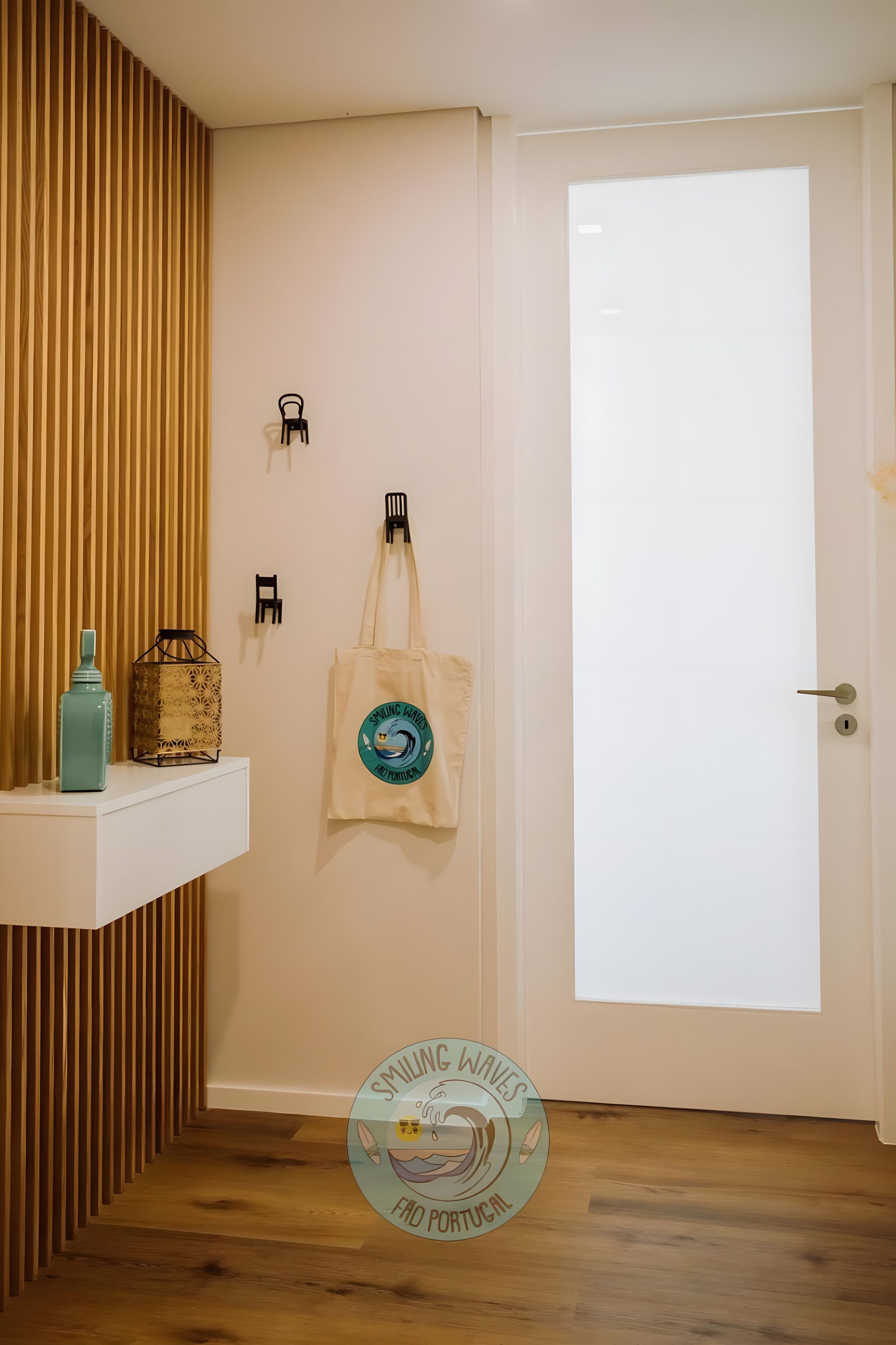 Une pièce avec un mur recouvert de lambris en bois, une porte blanche, une étagère sur laquelle se trouvent une bouteille et un objet décoratif, et un sac fixé au mur, orné d’un logo.