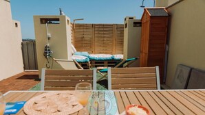 Eine Dachterrasse mit Esstisch, einer Holzterrasse und Blick auf die Umgebung.