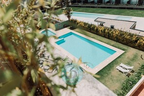 A swimming pool with a surrounding lawn and a few lounge chairs.