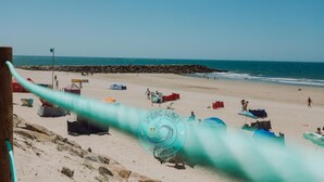 Ein Strand mit blauem Himmel, einem felsigen Wellenbrecher und einem Zeltbereich.