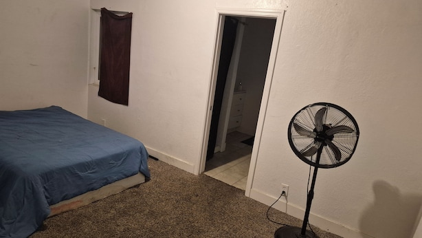 A bedroom with a bed, a standing fan, and a door leading to another room. - Welcoming to topspad in charming Fresno (Fresno)