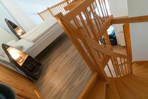 Eine Holzt Treppe führt zu einem Schlafzimmer mit einem weißen Bett und einer Heizung.
