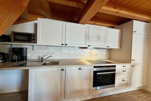 A kitchen with white cabinets, a microwave, a coffee maker, and a dishwasher. - Friesenhof "Dreilanden" - Kiek mol ut (Sankt Peter-Ording)