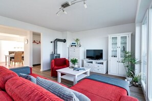 A modern living room with a red sofa, a television, and a cabinet. - Holiday apartment with 1 bedroom (Kappeln)