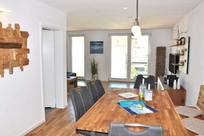A dining area with a wooden table, black chairs, and a hanging light fixture.