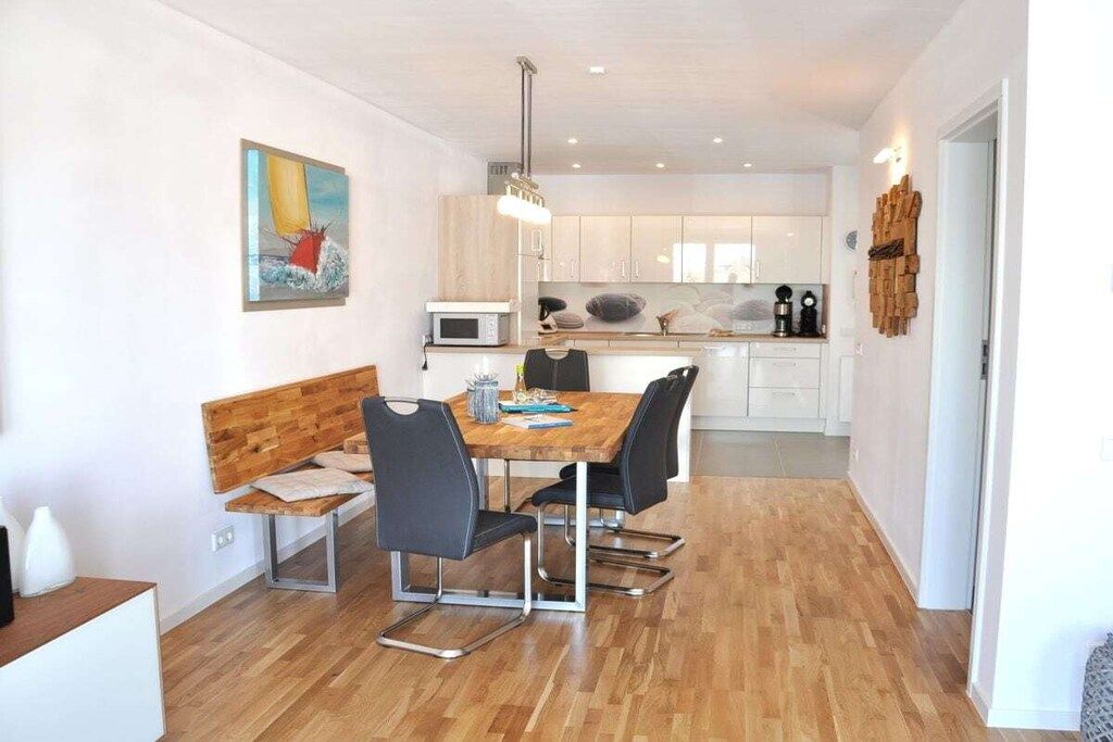 Eine moderne Küche mit weißen Schränken, einem Holztisch und schwarzen Stühlen.