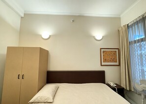 A hotel room with a bed, a wardrobe, a nightstand with a phone, and a window with curtains. - Modern Studio | Central Ultimo Broadway | Shared Kitchen & Laundry (Ultimo)