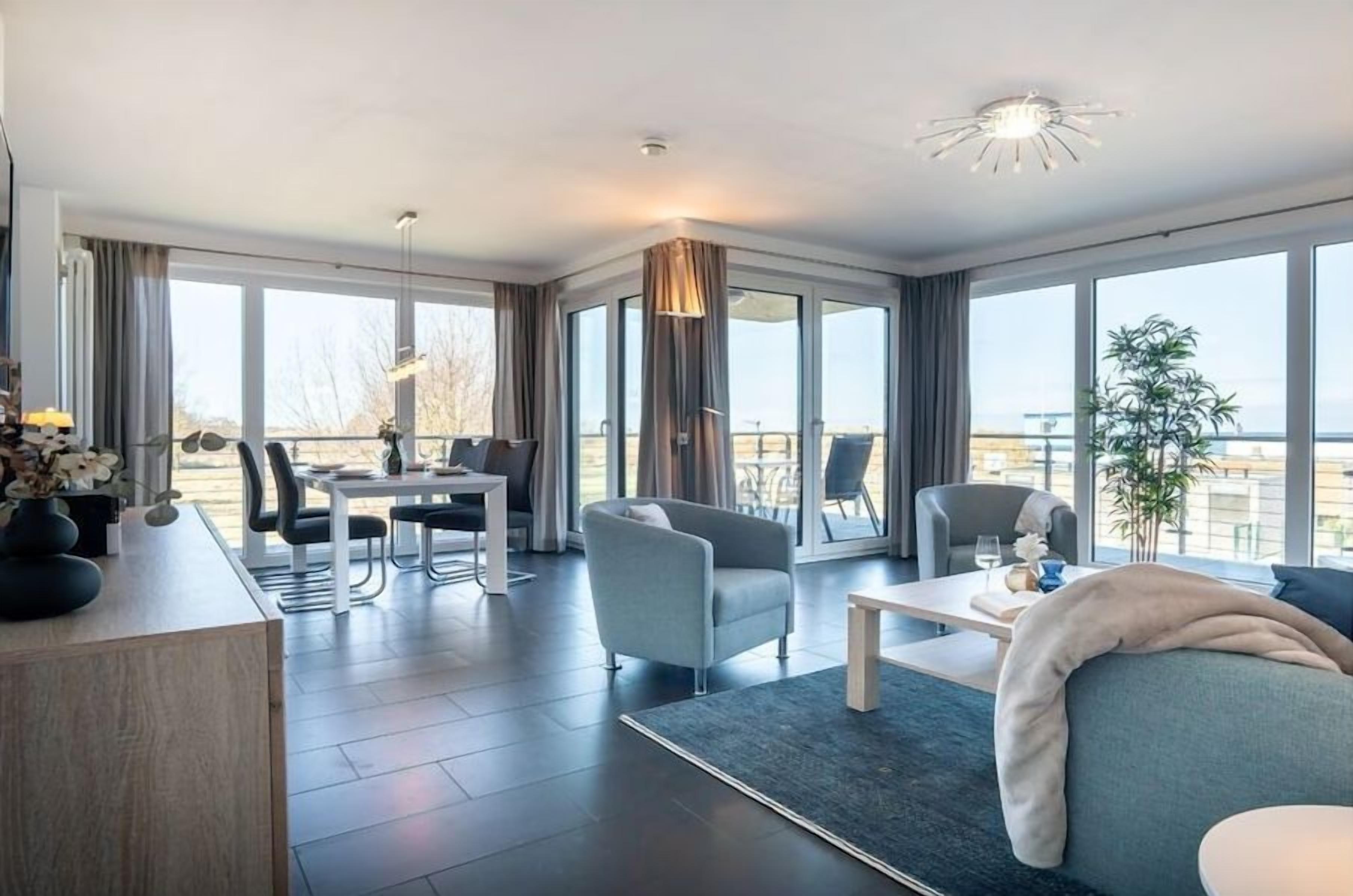 A modern hotel room with a large window, a dining area, and a seating area.