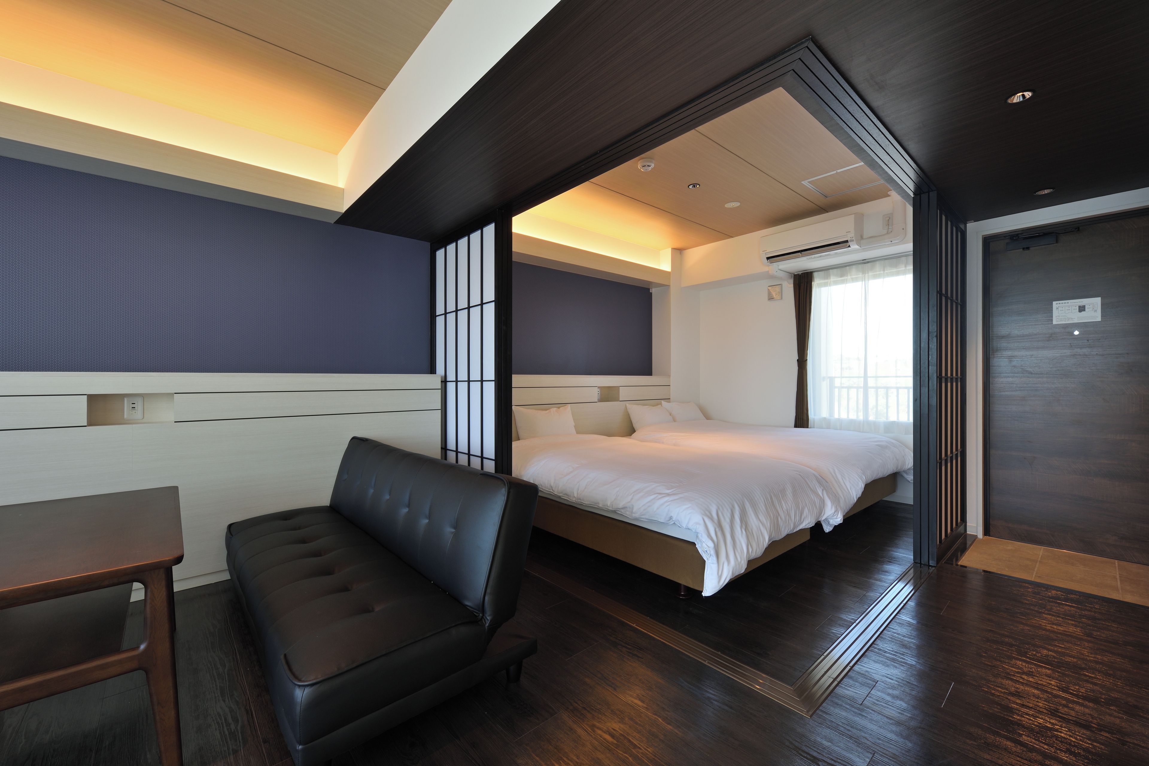 Una habitación de hotel moderna con cama, zona de estar y vistas al exterior.