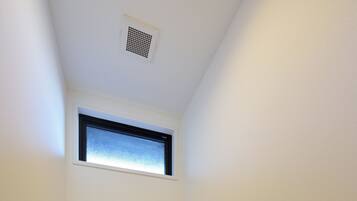 A small, narrow bathroom with a toilet, a window, and a toilet paper holder.