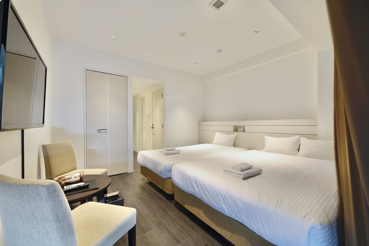 A hotel room with a bed, a chair, a desk, and a television.