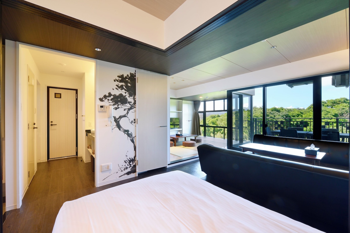 A modern hotel room with a large bed, a view of the outdoors, and a sliding door leading to a balcony.