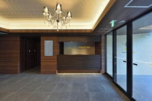 A reception area with a chandelier, a reception desk, and a glass wall. - Smile Smart Inn Okinawa Churaumi (Motobu, Kunigami District)
