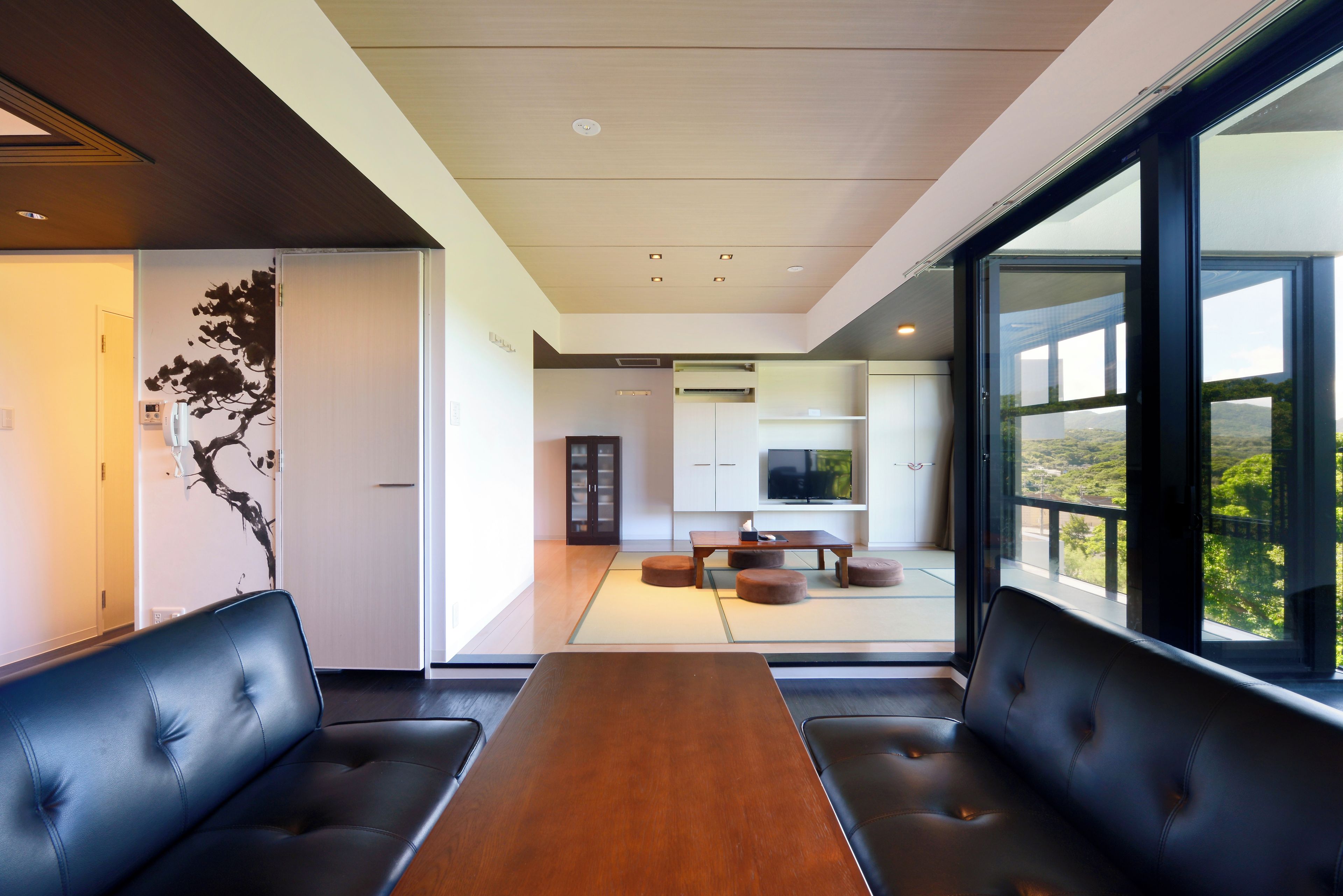 A modern interior with a dining area featuring a wooden table and black leather seating.