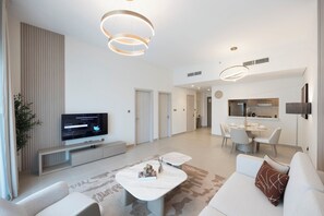 Una sala moderna con televisor de pantalla plana, un sofá, una mesa de centro y una zona de comedor con mesa y sillas.