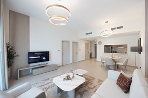 Una sala moderna con televisor de pantalla plana, un sofá, una mesa de centro y una zona de comedor con mesa y sillas.