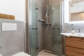 A modern bathroom with a glass-enclosed shower, a wooden vanity, and a white sink. - 4 in the Friesenhof - Starfish (Sankt Peter-Ording)