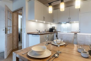 Eine moderne Küche mit weißen Schränken, einer Holz Arbeitsplatte und Pendelleuchten.