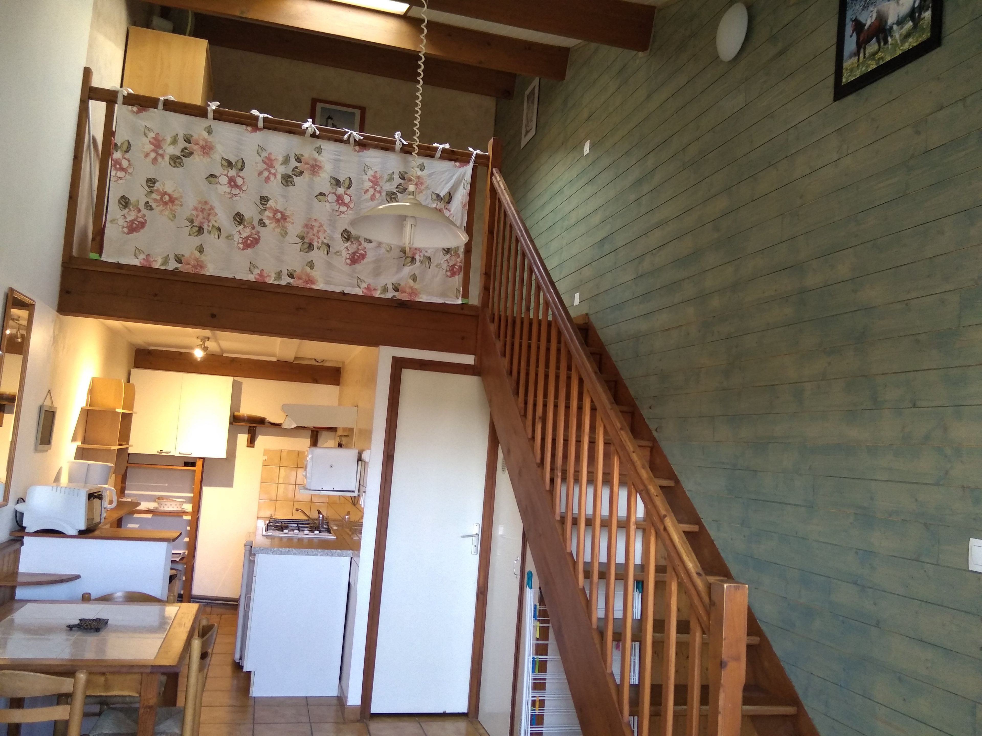 A multi-level wooden interior with a staircase, kitchen area, and dining space.
