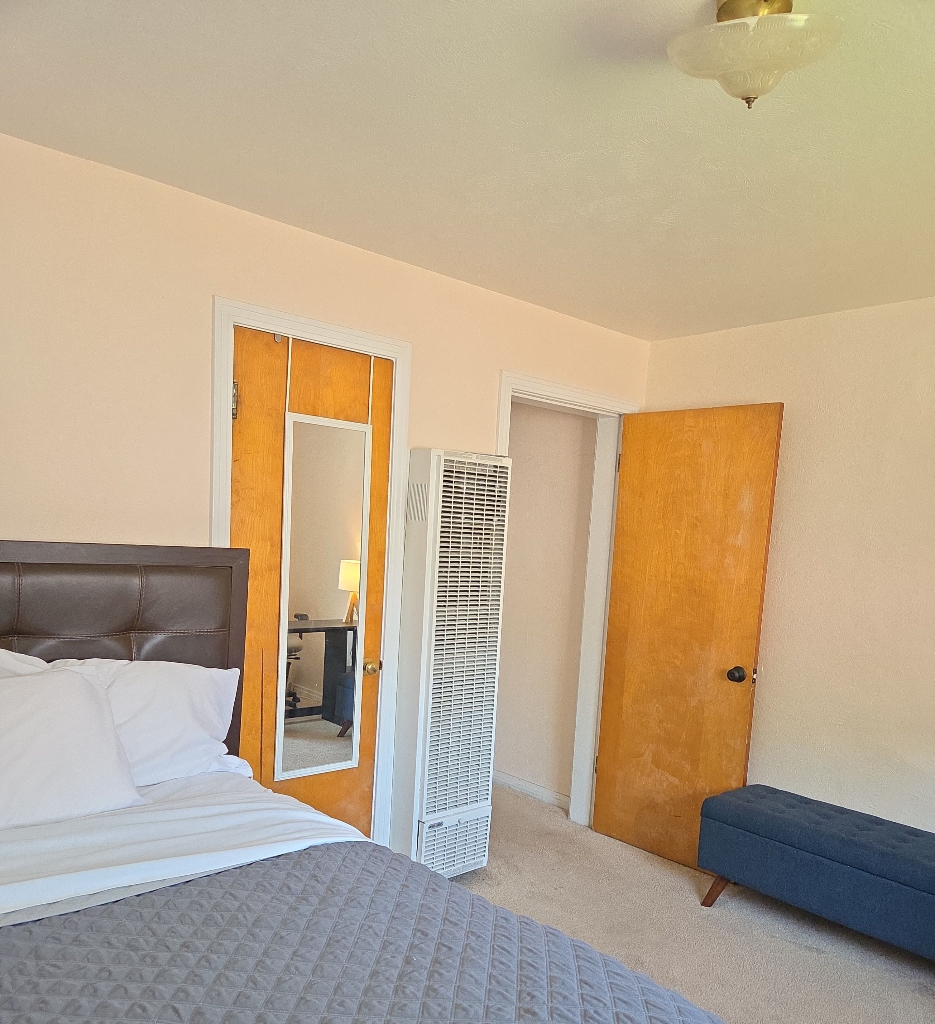 A bedroom with a bed, a desk, and a chair.