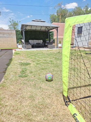 A patio area with outdoor furniture, a covered seating area, and a soccer goal.