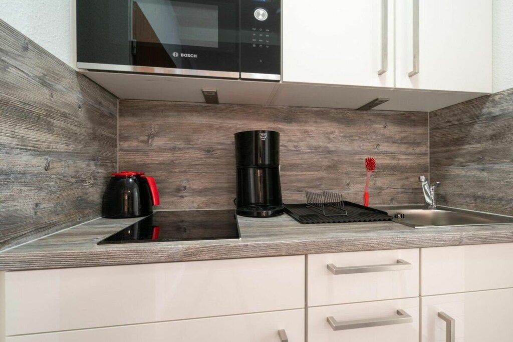 A kitchen with a Bosch microwave, a coffee maker, and a sink.
