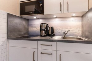 A modern kitchen with a Bosch microwave, a coffee maker, and a sink. - Utholm 2 beach shelter (St. Peter-Ording)
