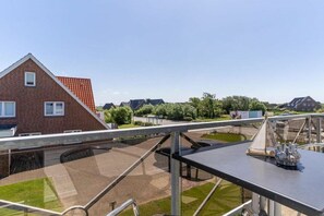 A residential area with a brick house, a paved walkway, and a small pond. - Utholm 2 beach shelter (St. Peter-Ording)