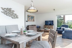 A modern living space with a dining area, a sofa, a television, and a view of the outdoors. - Cape Fred at the quayside (Kappeln)