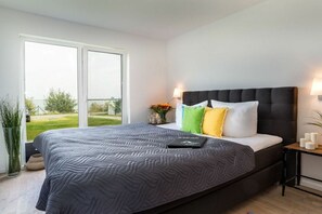 A bedroom with a large bed, a nightstand, a window, and a view of the outdoors. - Cape Fred at the quayside (Kappeln)