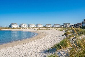 Ein Strandgrundstück mit mehreren weißen Gebäuden, einem Sandstrand und blauem Himmel.