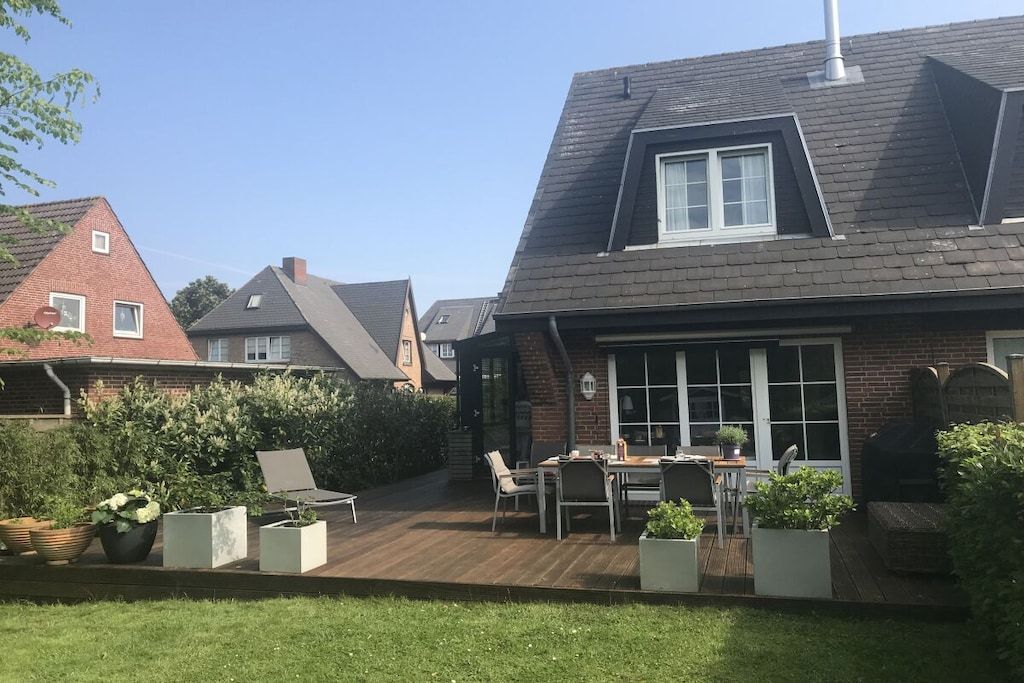 A residential property with a wooden deck, outdoor seating, and a brick house.