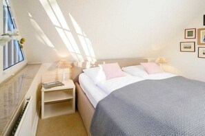 A bedroom with a bed, bedside tables, and a window with curtains. - Holiday home with 2 bedrooms (Sylt \/ OT Tinnum)