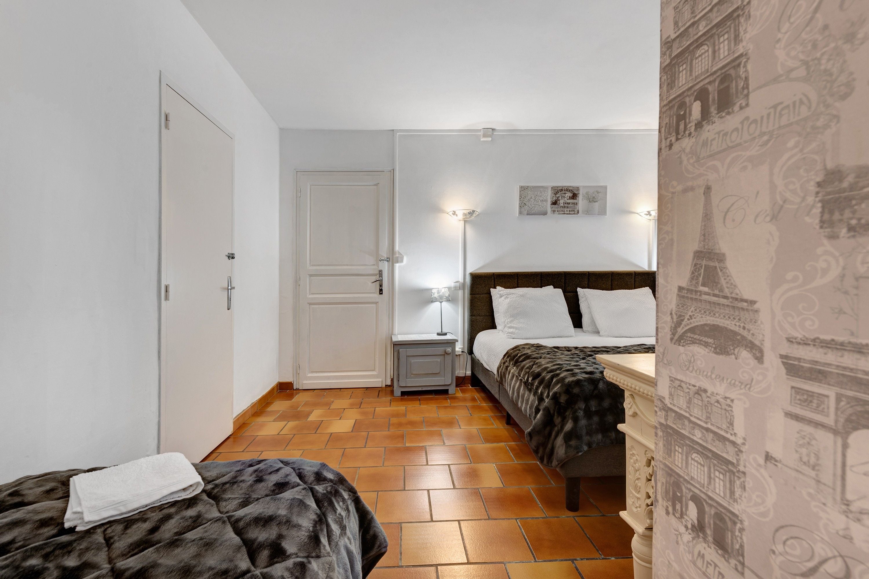 Une chambre d’hôtel avec un lit, une table de chevet, une lampe et une porte.