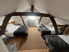 Et hyggeligt soveværelse på loftet med to senge, en kommode og en lampe.