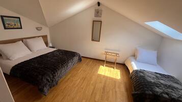 Une chambre avec deux lits, un puits de lumière, un plancher en bois et une petite table.
