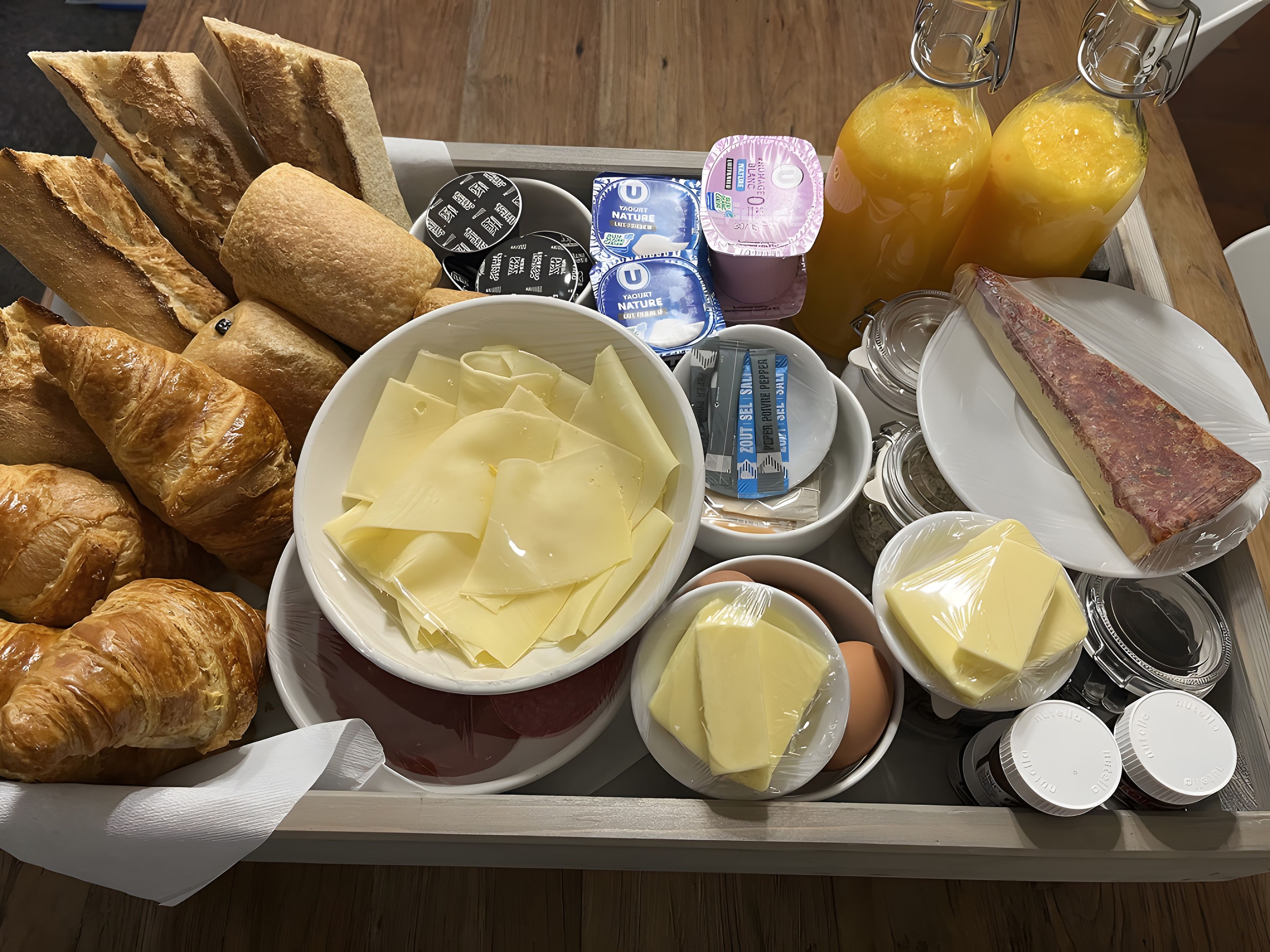 A tray with bread, cheese, butter, and juice.