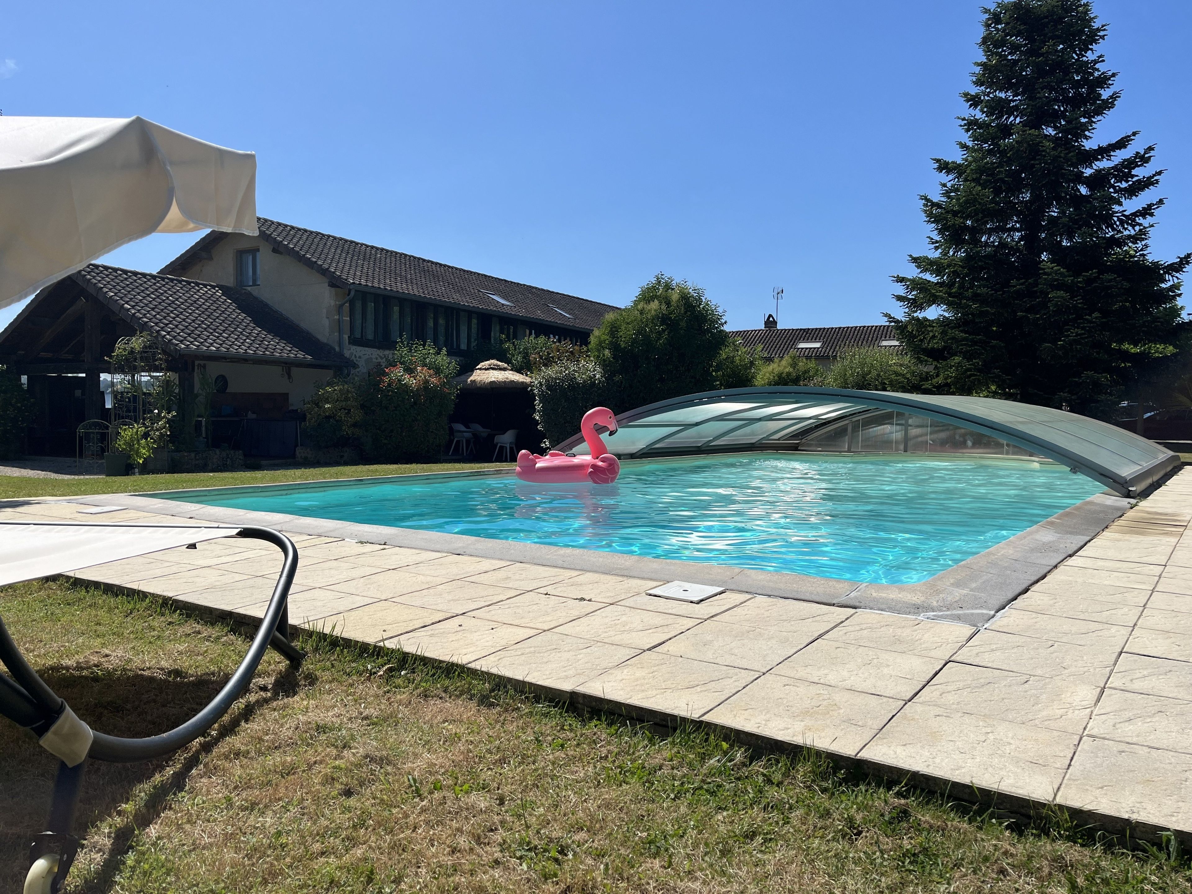 A swimming pool with a glass enclosure, a pink flamingo float, and a covered patio area.