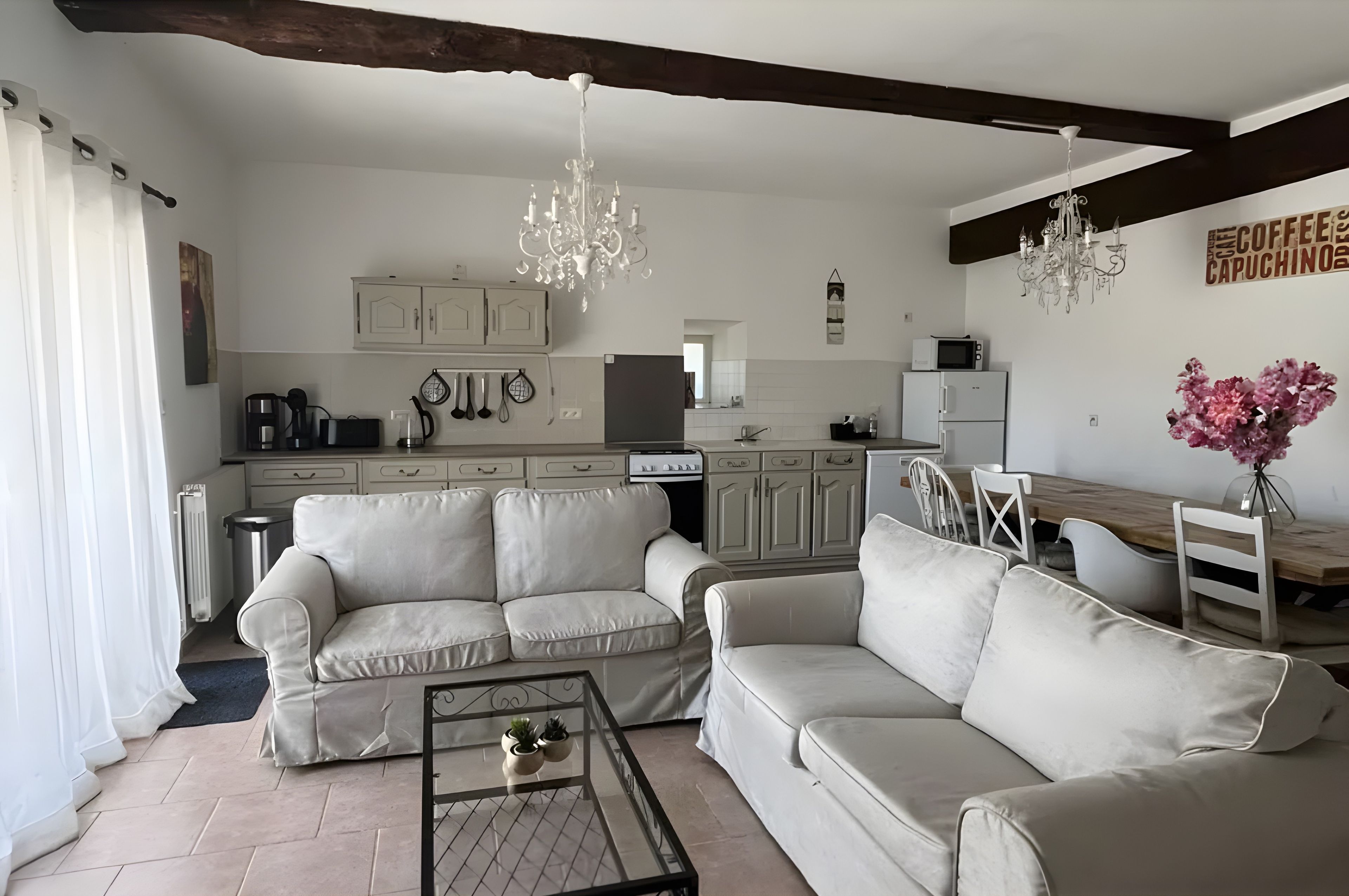 A modern living room with a sofa set, a coffee table, and a dining area with a wooden table and chairs.