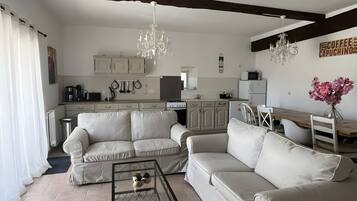 A modern living room with a sofa set, a coffee table, and a dining area with a wooden table and chairs.