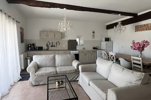 A modern living room with a sofa set, a coffee table, and a dining area with a wooden table and chairs.