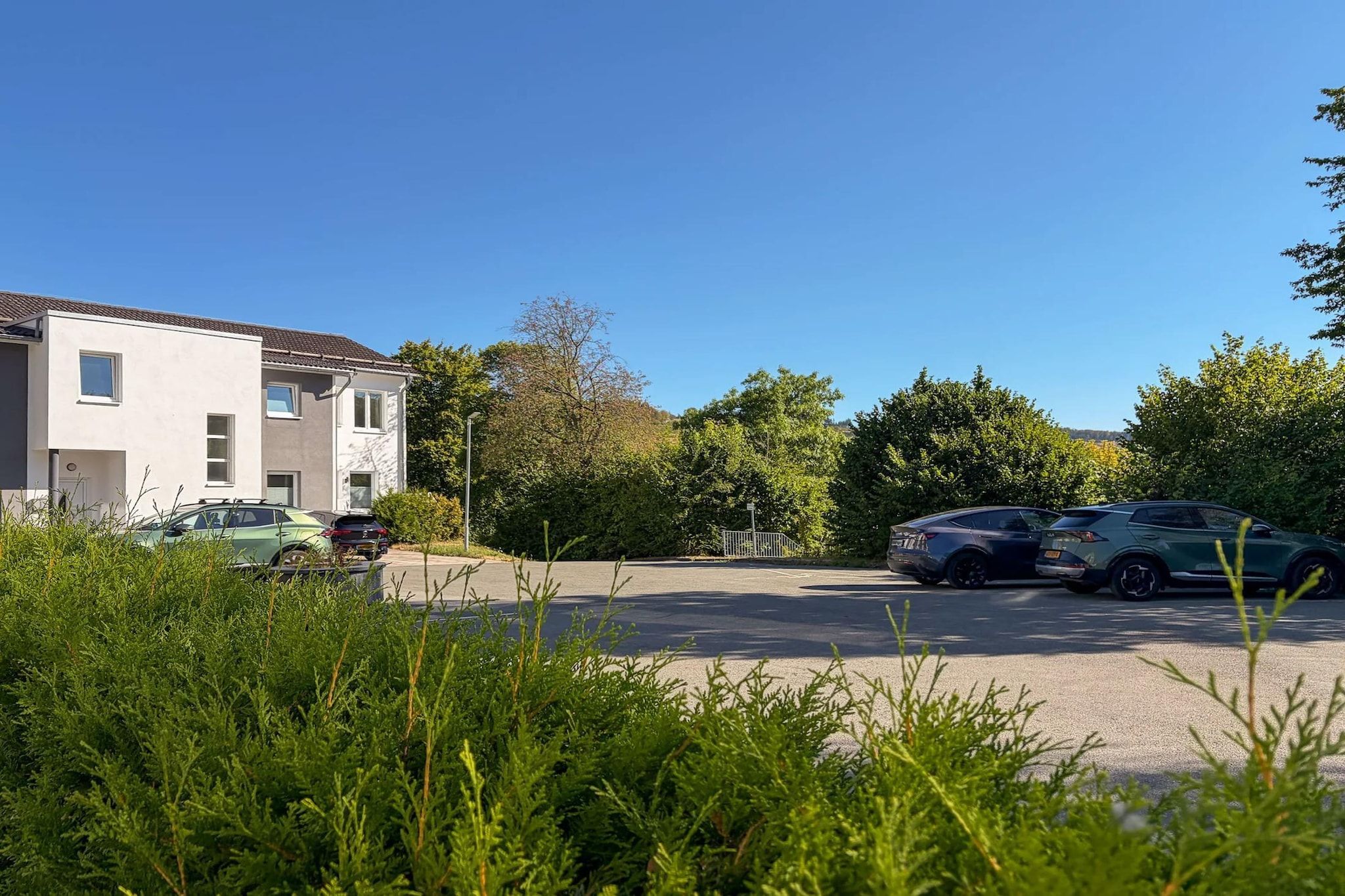 Una zona residencial con casas modernas, un estacionamiento y abundante vegetación.
