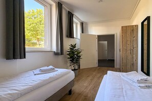 A hotel room with two beds, a potted plant, and a view of the outdoors. - Modern Apartment Retreat for 6 in Winterberg Züschen (Winterberg)