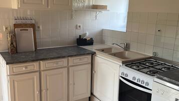 A kitchen with white cabinets, a stove, and a sink.